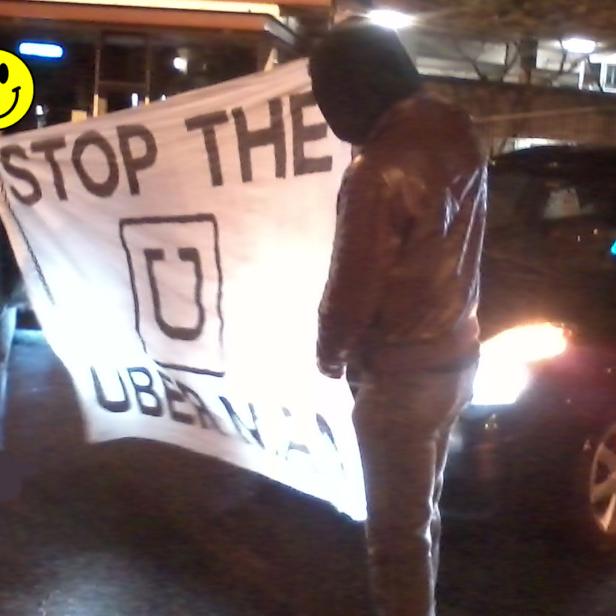 Zwei Personen halten ein Transparent mit der Aufschrift „Stop the Ubernacht“.