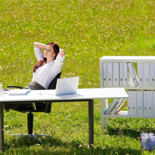 Young businesswoman in sunny meadow nature office relaxing behind table