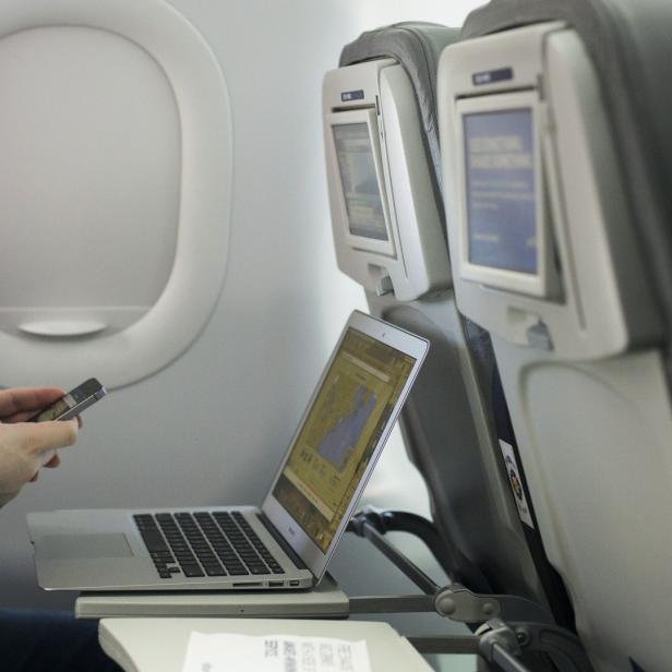 A man uses his mobile phone and laptop to test a new high speed inflight Internet service named Fli-Fi while on a special JetBlue media flight out of John F. Kennedy International Airport in New York December 11, 2013. Wi-Fi in the sky is taking off, promising much better connections for travelers and a bonanza for the companies that sell the systems. With satellite-based Wi-Fi, Internet speeds on jetliners are getting lightning fast. And airlines are finding that travelers expect connections in the air to rival those on the ground - and at lower cost. Picture taken December 11, 2013. To match Analysis AIRLINES-WIFI/ REUTERS/Lucas Jackson (UNITED STATES - Tags: TRANSPORT BUSINESS SCIENCE TECHNOLOGY TELECOMS TRAVEL)