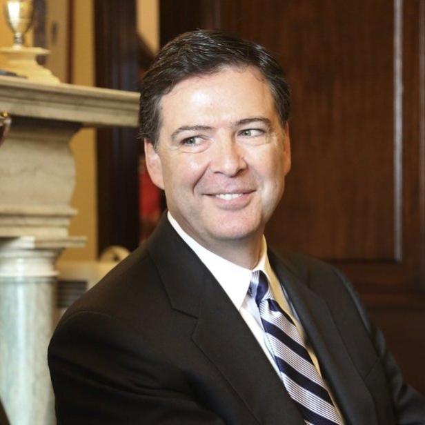 James Comey lächelt während eines Gesprächs mit einer anderen Person.
