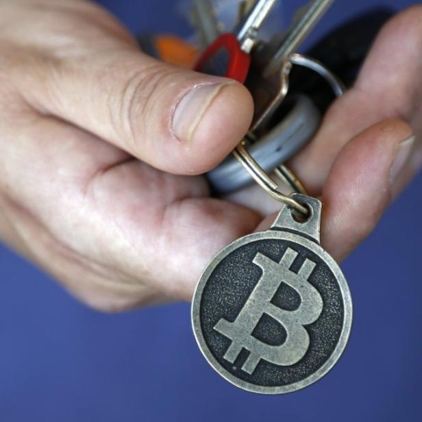 Eine Hand hält einen Schlüsselanhänger mit einem Bitcoin-Symbol.