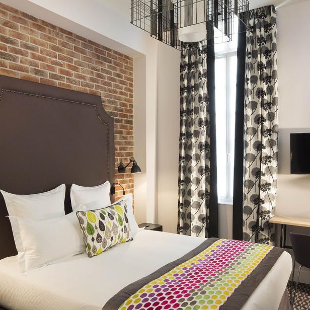 Ein Hotelzimmer mit einem Doppelbett vor einer Ziegelwand.