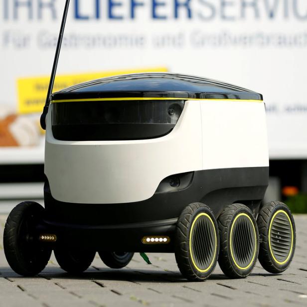 Ein autonomer Lieferroboter steht vor einem Lieferwagen von Metro.