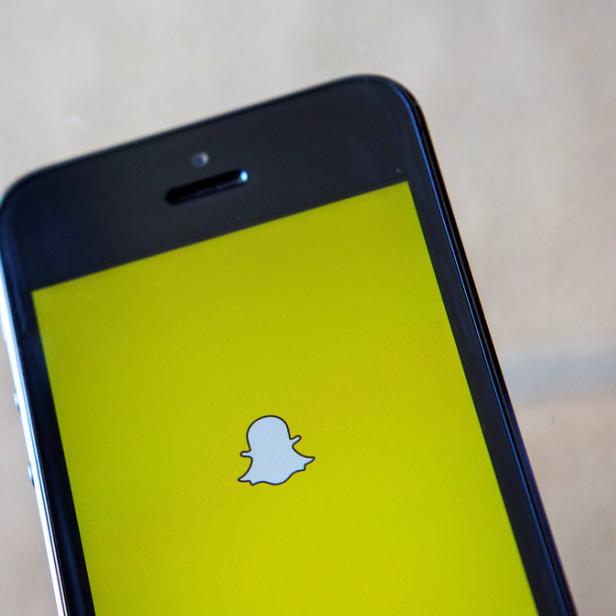 Ein Smartphone zeigt das Snapchat-Logo auf gelbem Hintergrund.
