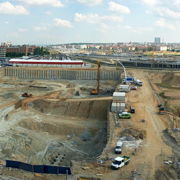 Eine Großbaustelle in einer Stadtlandschaft mit Baukränen und Erdbewegungsmaschinen.