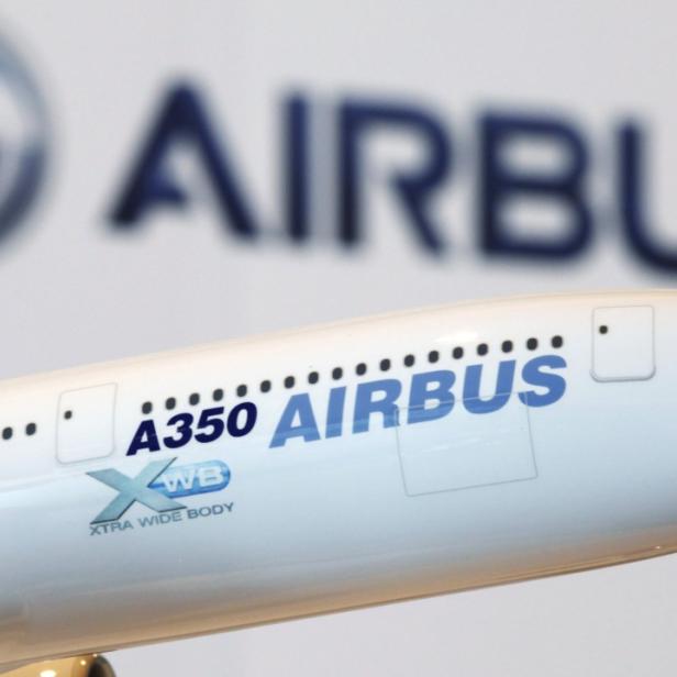 Nahaufnahme eines Airbus A350-Flugzeugmodells vor einem Airbus-Logo.