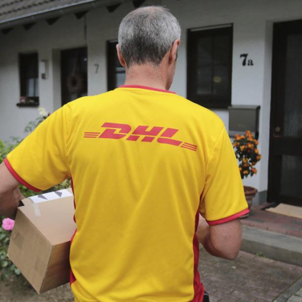 Ein DHL-Paketzusteller liefert ein Paket aus