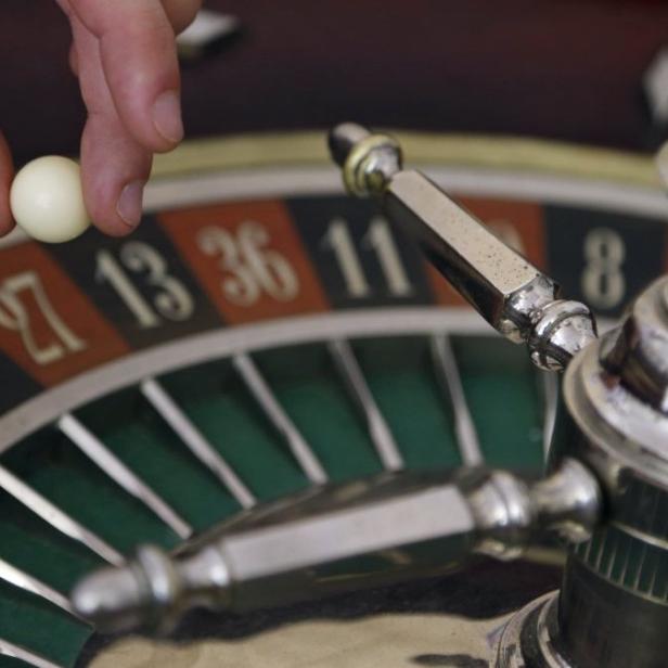 Eine Hand legt eine Kugel auf ein Roulette-Rad.