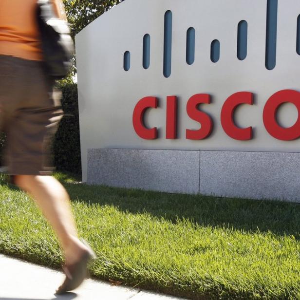 Eine Person geht an einem Schild mit der Aufschrift „Cisco“ vorbei.