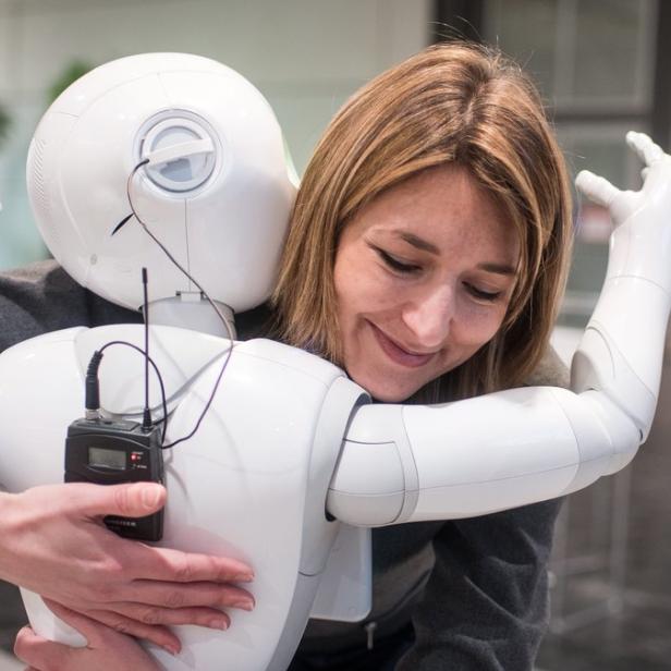 Eine Frau umarmt einen weißen Roboter.