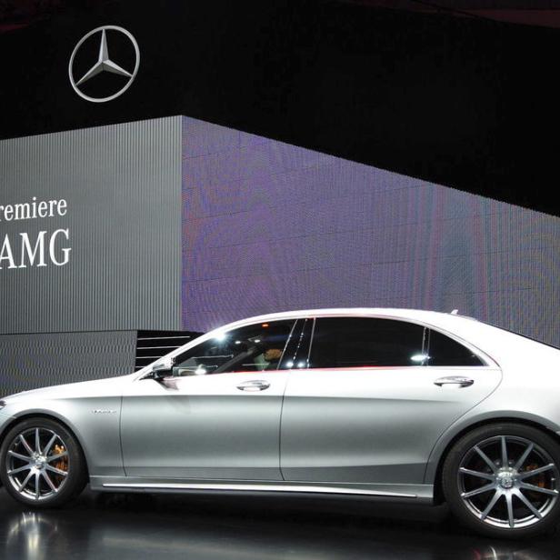 Ein silberner Mercedes-Benz S 63 AMG auf einer Bühne vor einer Leinwand.