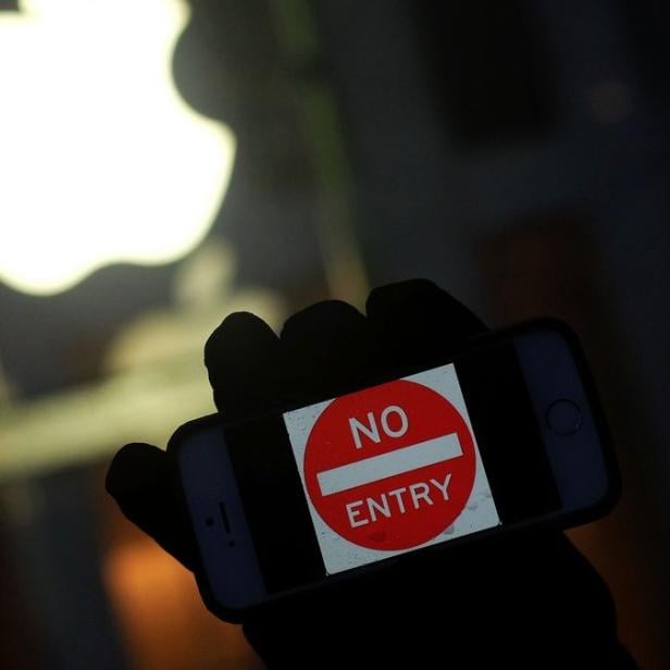 Demonstrant mit einem &quot;No Entry&quot;-Schriftzug auf seinem iPhone vor einem Apple Store