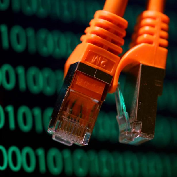 Zwei orangefarbene Netzwerkkabel vor einem Hintergrund aus binärem Code.