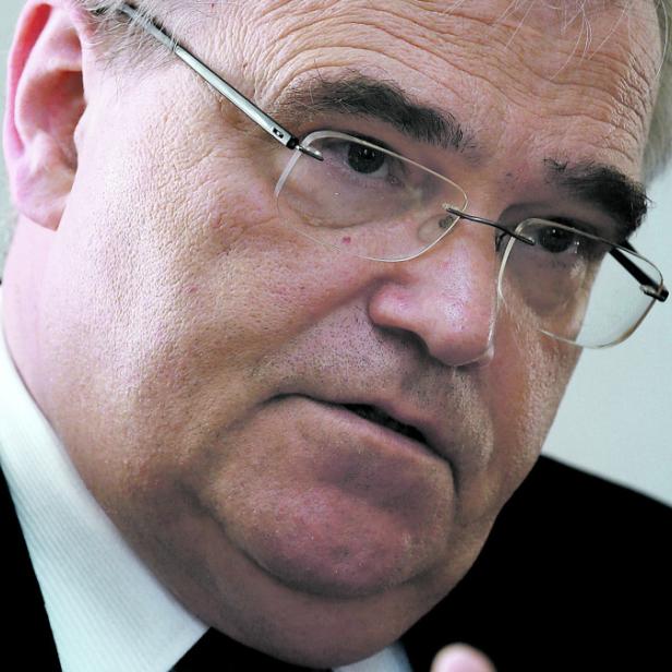 Ein Mann mit Brille und dunklem Anzug blickt aufmerksam in die Kamera.
