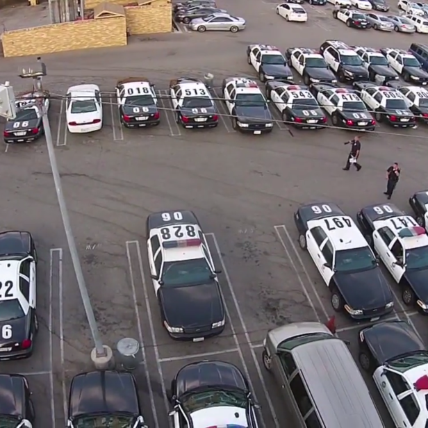 Luftaufnahme eines Parkplatzes voller schwarz-weißer Polizeiautos.