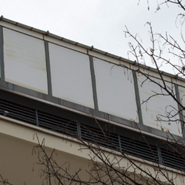 Ein Gebäude mit einem Aufbau aus weißen Paneelen und Überwachungskameras auf dem Dach.