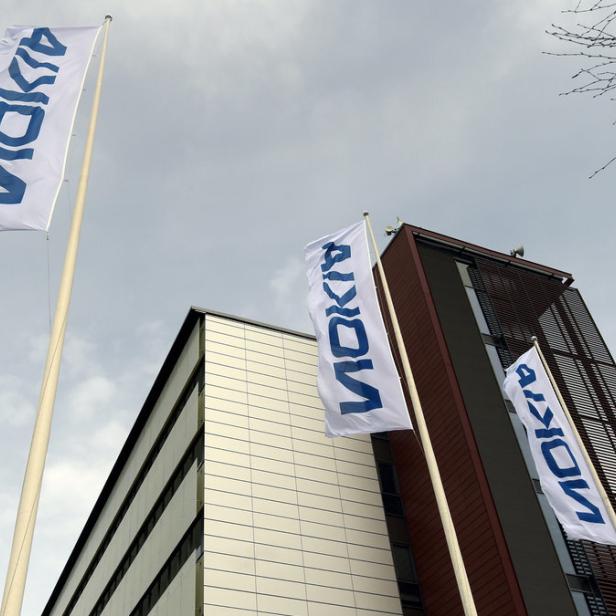 Drei Nokia-Flaggen wehen vor einem modernen Bürogebäude.