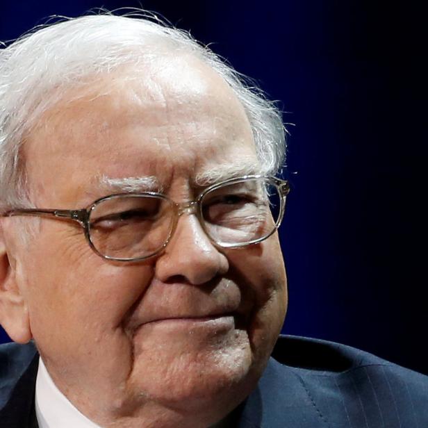 Warren Buffett mit Brille vor einem dunklen Hintergrund.