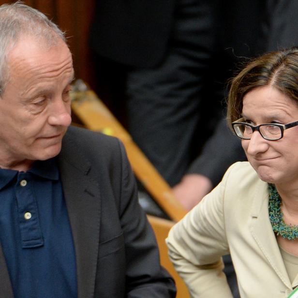 Ein Mann und eine Frau stehen nebeneinander, die Frau mit einer grünen Halskette und Brille.