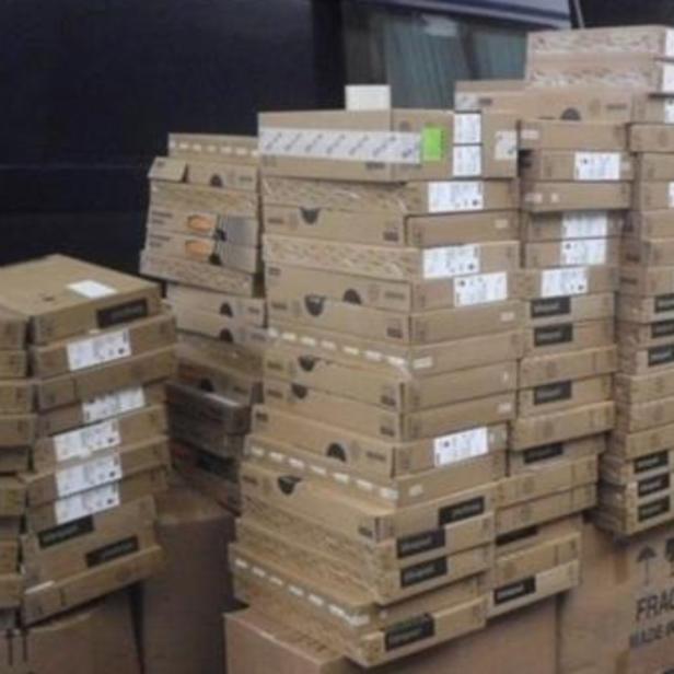 Viele Kartons mit Laptops werden aus einem Lieferwagen geladen.