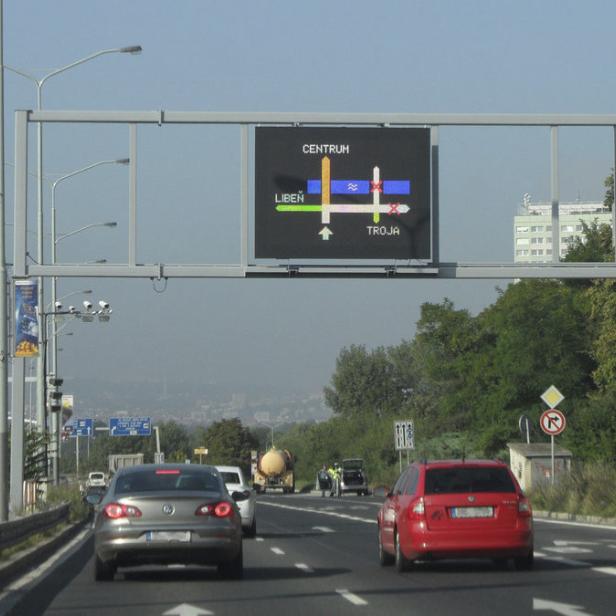 Verkehr auf einer Straße in Prag mit einem Wegweiser nach Centrum, Libeň und Troja.