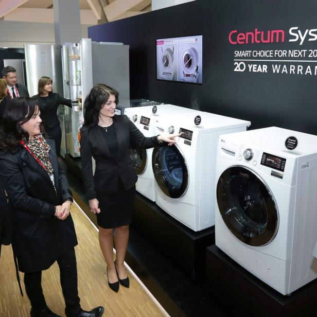 Auf einem Messestand präsentiert eine Frau Waschmaschinen der Marke LG Centum System.
