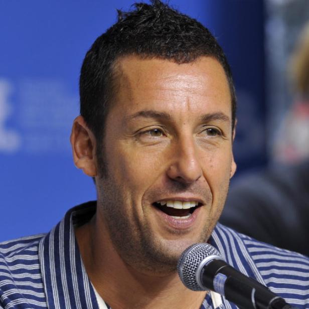 Adam Sandler lächelt in ein Mikrofon.