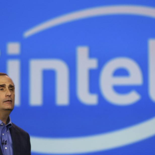 Ein Mann steht vor einem blauen Hintergrund mit dem Intel-Logo.