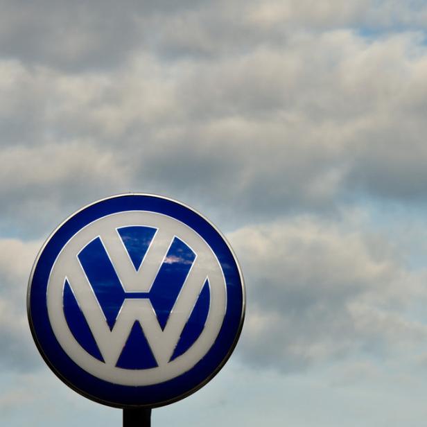Ein blau-weißes Volkswagen-Logo vor einem bewölkten Himmel.