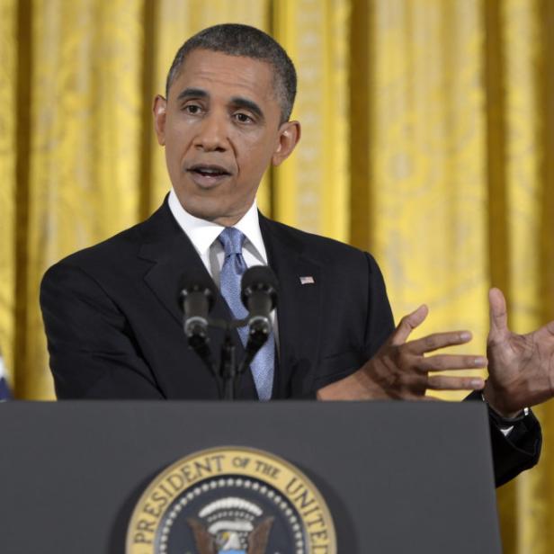 Barack Obama spricht vor Flaggen der USA und des Präsidenten.
