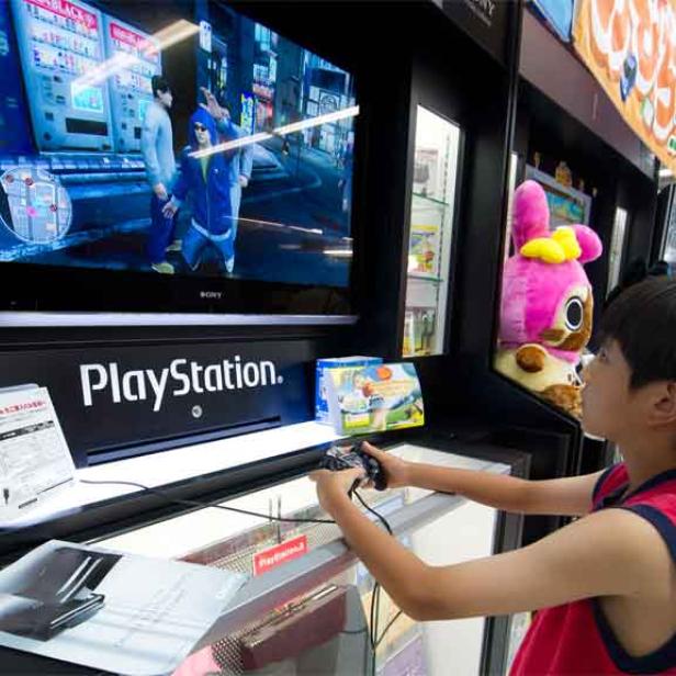 Ein Junge spielt an einer PlayStation in einem Geschäft.