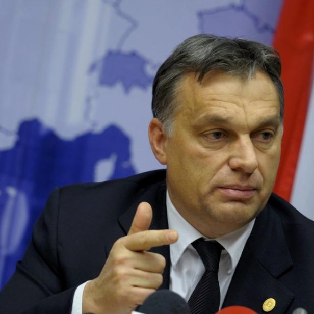 Viktor Orbán gestikuliert vor einer ungarischen Flagge.