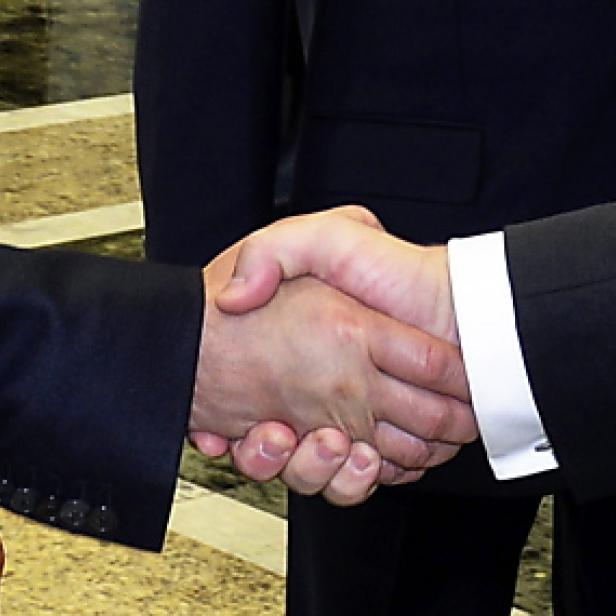 Zwei Personen in Anzügen geben sich die Hand.