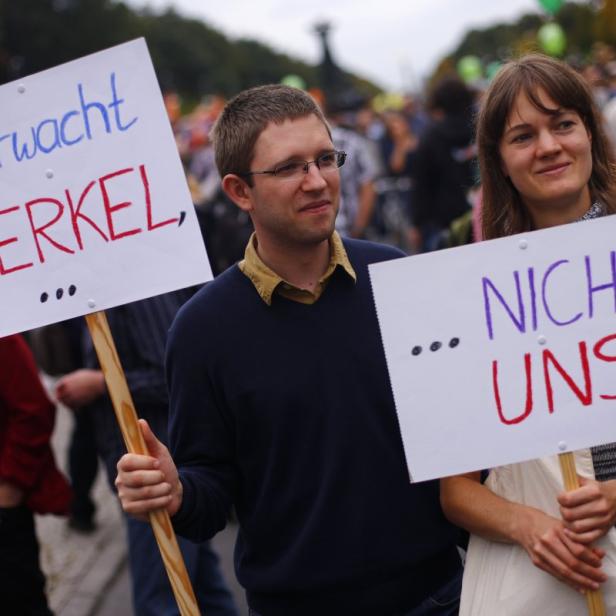 Zwei Demonstranten halten Schilder mit der Aufschrift „Überwacht Merkel“ und „Nicht uns“.