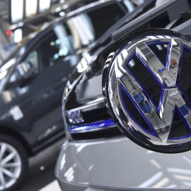 Das VW-Logo an einem Auto in einer Produktionshalle.