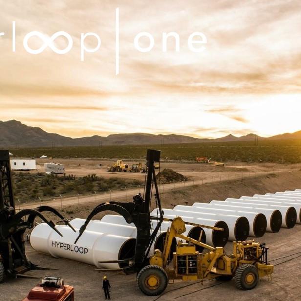 Eine Baustelle für Hyperloop-Röhren in einer Wüstenlandschaft bei Sonnenuntergang.