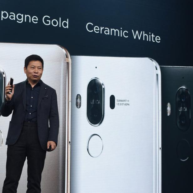 Ein Mann präsentiert drei Huawei-Smartphones in den Farben Champagner Gold, Keramikweiß und Schwarz.