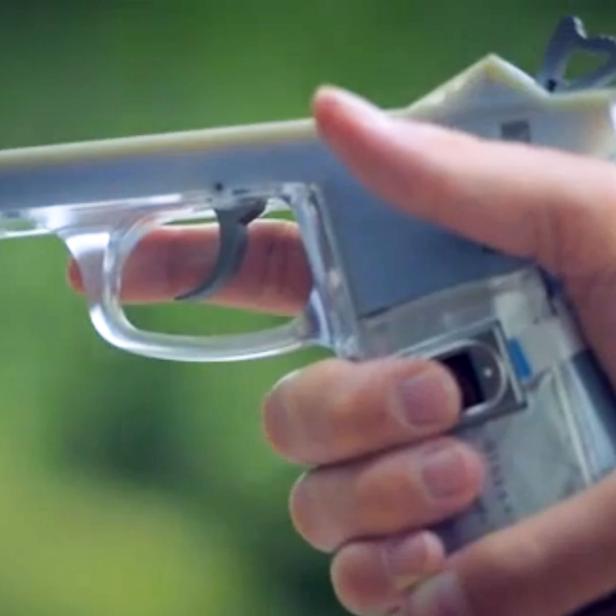 Eine Hand hält eine durchsichtige Spielzeugpistole.