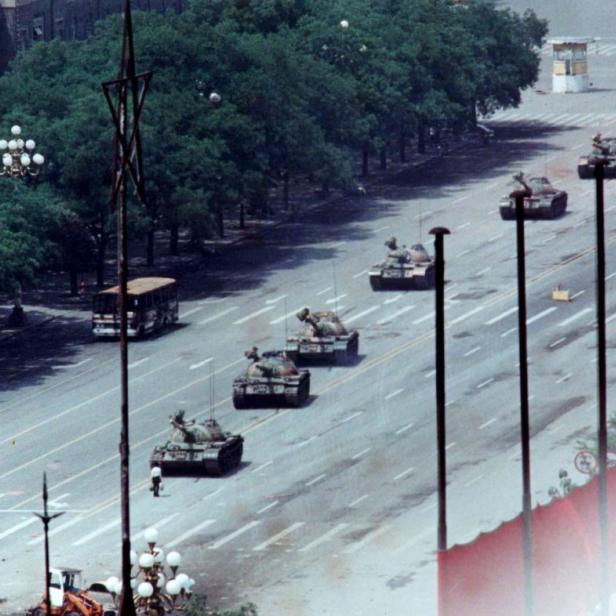 Eine Reihe von Panzern fährt eine breite Straße entlang.
