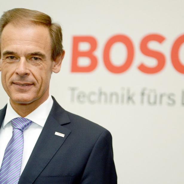 Ein Mann im Anzug steht vor einem Bosch-Logo.