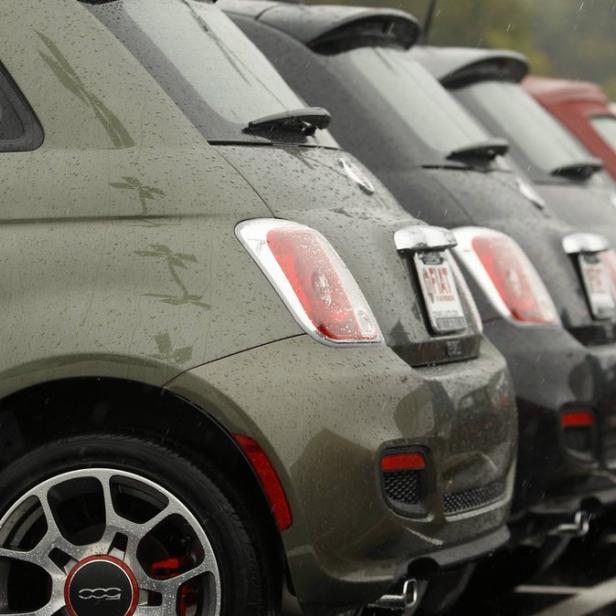 Mehrere Fiat 500 stehen im Regen in einer Reihe.