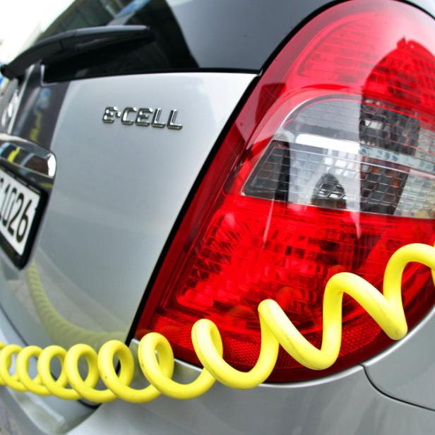Ein Opel e-Cell wird mit einem gelben Kabel an einer Ladestation aufgeladen.