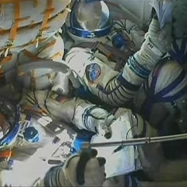 Mehrere Astronauten in Raumanzügen in einem Raumschiff.