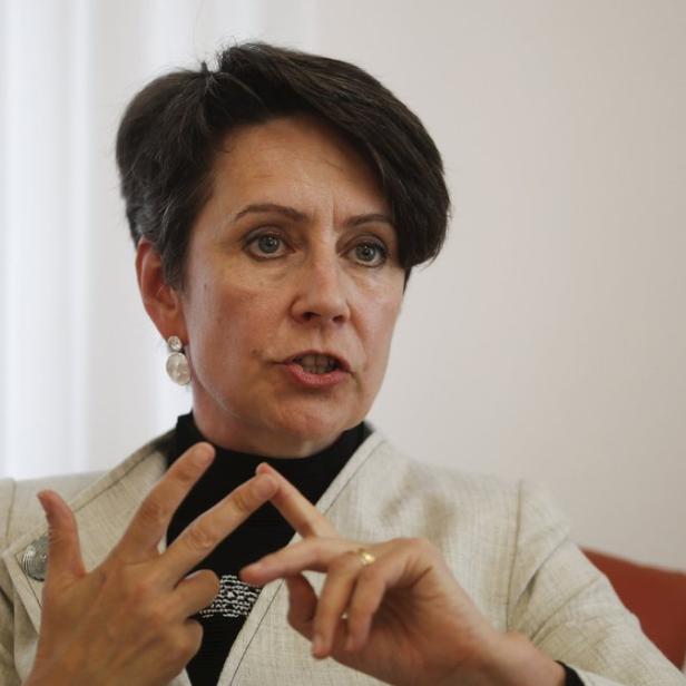 Eine Frau mit kurzem, dunklem Haar gestikuliert während eines Gesprächs.