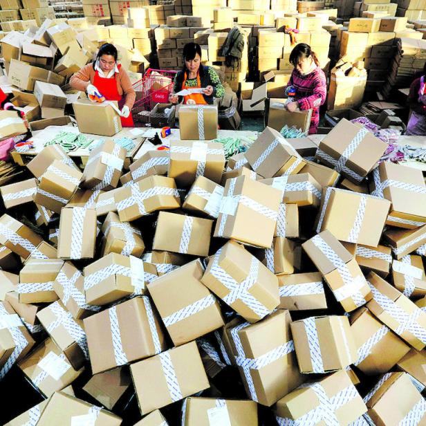 Frauen verpacken Pakete in einem Lager voller Kartons.