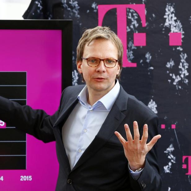Ein Mann mit Brille präsentiert eine Grafik mit Zahlen vor einem T-Mobile-Hintergrund.