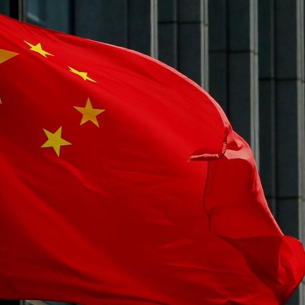 Die Nationalflagge Chinas weht vor einem modernen Gebäude.