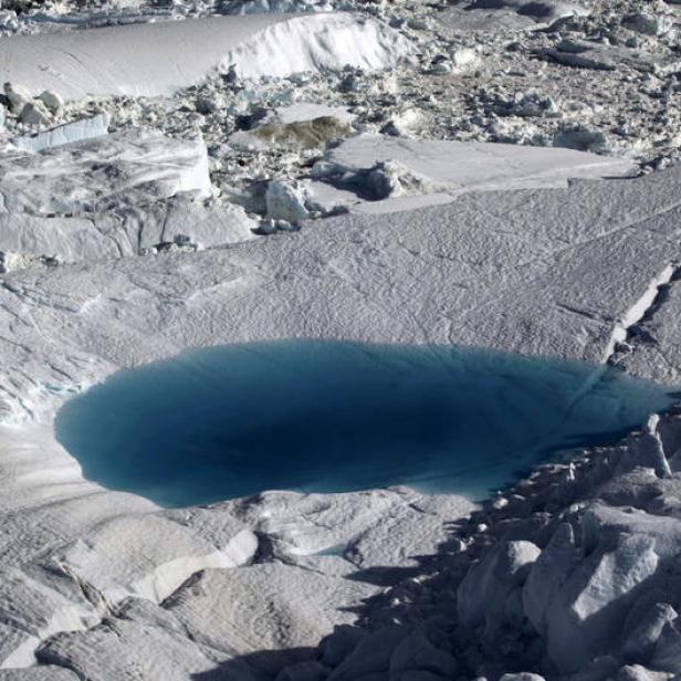 Ein tiefblauer See inmitten einer eisigen, schneebedeckten Landschaft.