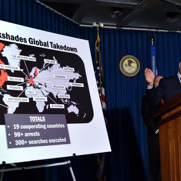 Ein Mann spricht an einem Rednerpult vor einer Karte, die die „Blackshades Global Takedown“-Operation zeigt.