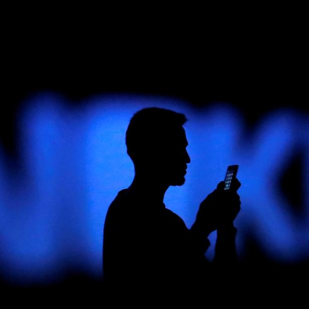 Die Silhouette eines Mannes, der ein Smartphone vor einem blauen Nokia-Logo benutzt.